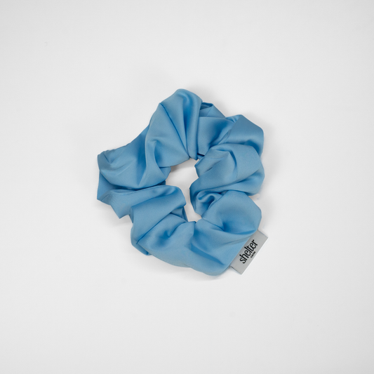 Blue scrunchie with a brand tag on a white background