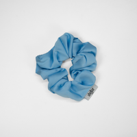 Blue scrunchie with a brand tag on a white background