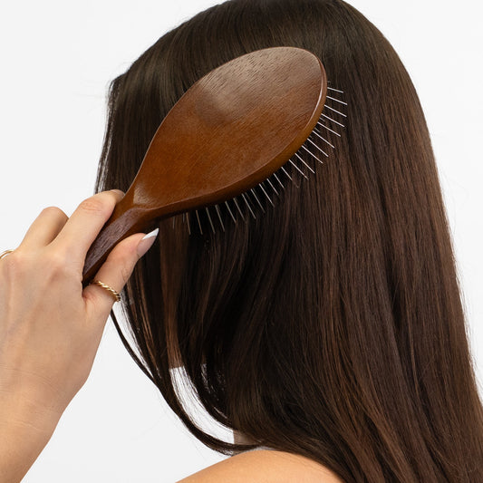 Awakening Hair Brush with a wooden handle, gently detangling long, straight hair.